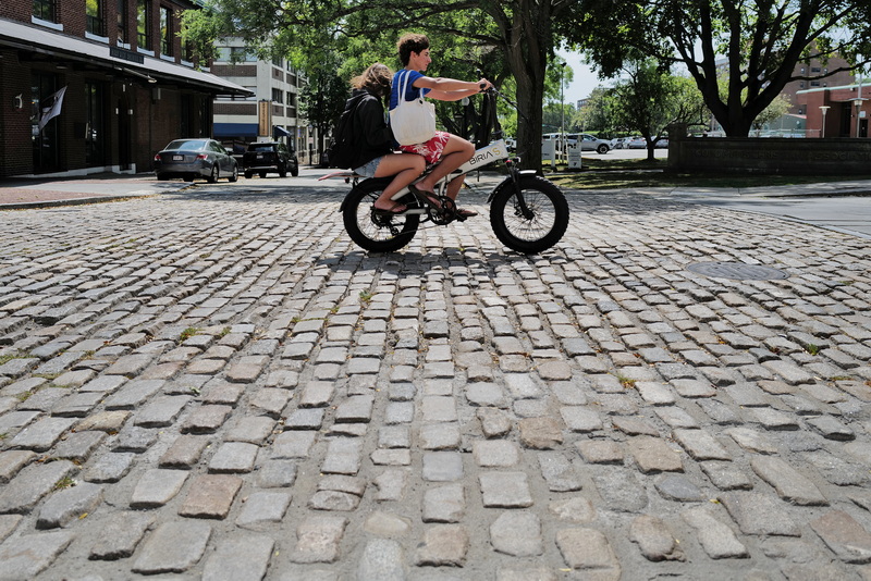 A young man and young woman ride an e-bicycle on the cobbled section of Union Street in New Bedford, MA on August 27, 2026. PHOTO PETER PEREIRA