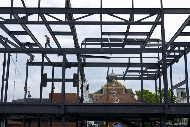 On September 3, 2026, an ironworker walks across the frame of the future New Bedford Whaling Museum Welcome & Exhibition Center being constructed across from the historic museum seen in the distance. PHOTO PETER PEREIRA