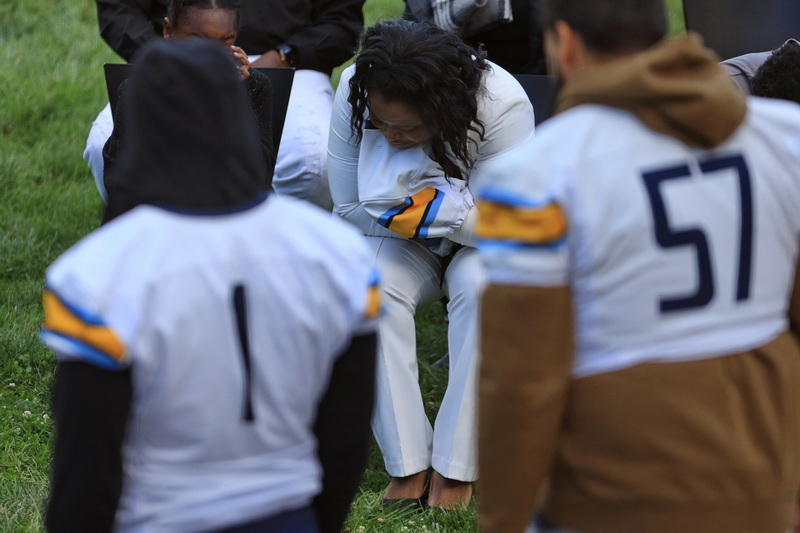Marvins Antoine's mother holds onto a her son's jersey given to her by his UMass Dartmouth football teammates during a vigil honoring him on September 23, 2026 at UMass Dartmouth.  Marvins Antoine was stabbed to death in Providence last weekend. PHOTO PETER PEREIRA