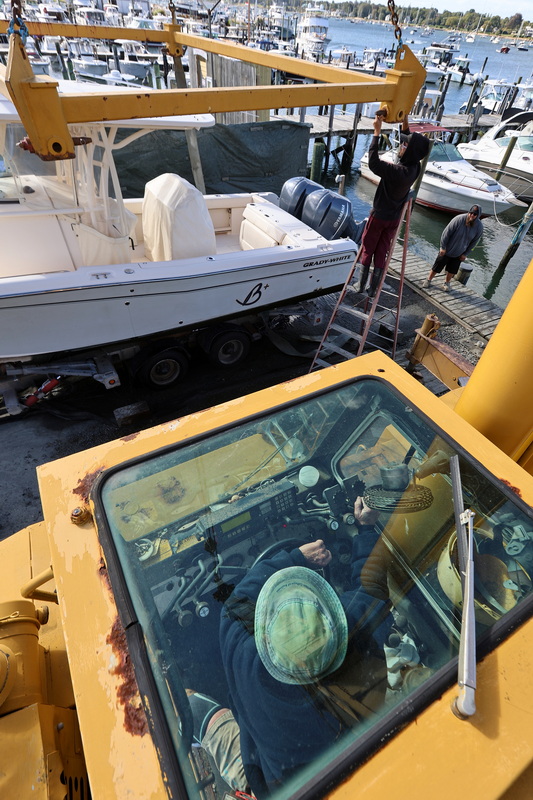 Jim Tripp, owner of Davis & Tripp Marina in Dartmouth, MA, is viewed through the glass top of his crane as he and his crew lift a powerboat out of the water on September 24, 2026, as a storm front approaches the region. PHOTO PETER PEREIRA