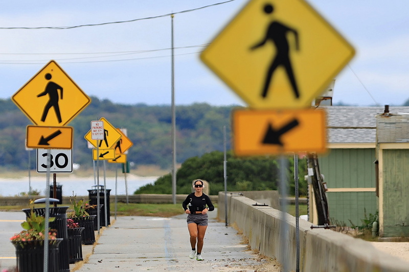 A woman is guided by signs as she runs on the sidewalk along East Rodney French Boulevard in New Bedford, MA on September 29, 2026. PHOTO PETER PEREIRA