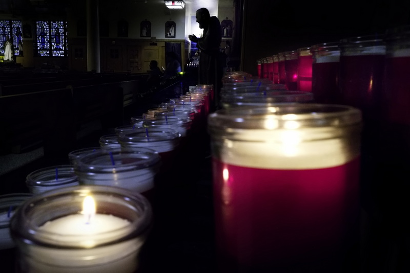 A statue of Father Pio is silhouetted at the end of the votive candles as a parishioner sits in silence on one of the pews of Our Lady�s Chapel in New Bedford, MA on September 30, 2026. PHOTO PETER PEREIRA