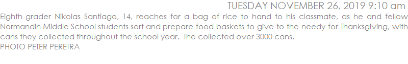Eighth grader Nikolas Santiago, 14, reaches for a bag of rice to hand to his classmate, as he and fellow Normandin Middle School students sort and prepare food baskets to give to the needy for Thanksgiving, with cans they collected throughout the school year.  The collected over 3000 cans.