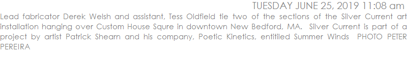Lead fabricator Derek Welsh and assistant, Tess Oldfield tie two of the sections of the Silver Current art installation hanging over Custom House Squre in downtown New Bedford, MA.  Silver Current is part of a project by artist Patrick Shearn and his company, Poetic Kinetics, entitiled Summer Winds  PHOTO PETER PEREIRA