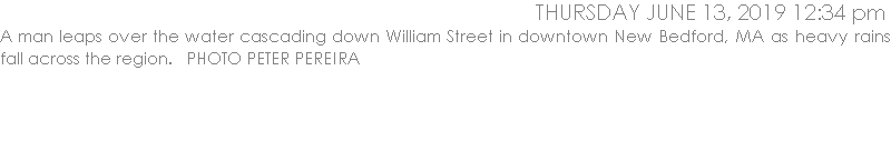 A man leaps over the water cascading down William Street in downtown New Bedford, MA as heavy rains fall across the region.   PHOTO PETER PEREIRA