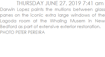 Darwin Lopez paints the mullions between glass panes on the iconic extra large windows of the Lagoda room at the Whaling Musem in New Bedford as part of extensive exterior restoration. 