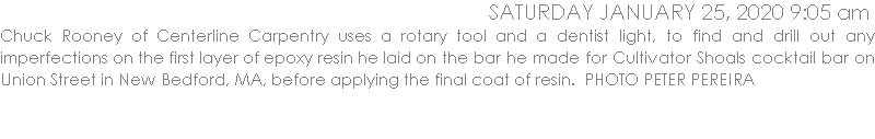Chuck Rooney of Centerline Carpentry uses a rotary tool and a dentist light, to find and drill out any imperfections on the first layer of epoxy resin he laid on the bar he made for Cultivator Shoals cocktail bar on Union Street in New Bedford, MA, before applying the final coat of resin.  PHOTO PETER PEREIRA