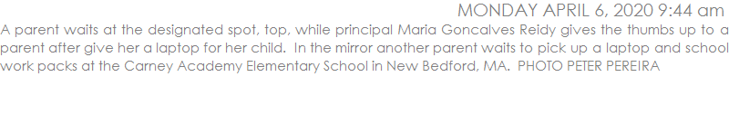 A parent waits at the designated spot, top, while principal Maria Goncalves Reidy gives the thumbs up to a parent after give her a laptop for her child.  In the mirror another parent waits to pick up a laptop and school work packs at the Carney Academy Elementary School in New Bedford, MA.  PHOTO PETER PEREIRA