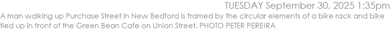 A man walking up Purchase Street in New Bedford is framed by the circular elements of a bike rack and bike tied up in front of the Green Bean Cafe on Union Street. PHOTO PETER PEREIRA