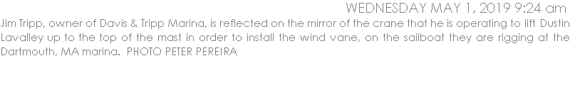 Jim Tripp, owner of Davis & Tripp Marina, is reflected on the mirror of the crane that he is operating to lift Dustin Lavalley up to the top of the mast in order to install the wind vane, on the sailboat they are rigging at the Dartmouth, MA marina.  PHOTO PETER PEREIRA