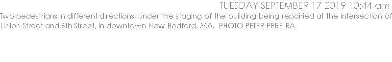 Two pedestrians in different directions, under the staging of the building being repairied at the intersection of Union Street and 6th Street, in downtown New Bedford, MA.  PHOTO PETER PEREIRA