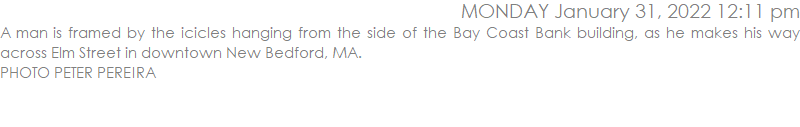 A man is framed by the icicles hanging from the side of the Bay Coast Bank building, as he makes his way across Elm Street in downtown New Bedford, MA.