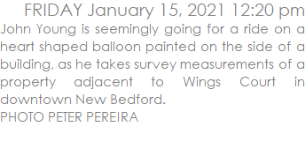 John Young is seemingly going for a ride on a heart shaped balloon painted on the side of a building, as he takes survey measurements of a property adjacent to Wings Court in downtown New Bedford. PHOTO PETER PEREIRA