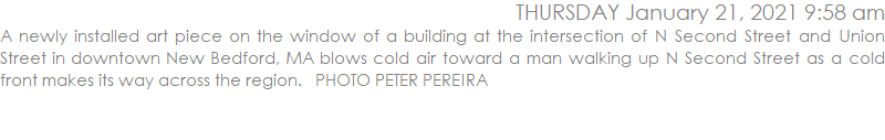 A newly installed art piece on the window of a building at the intersection of N Second Street and Union Street in downtown New Bedford, MA blows cold air toward a man walking up N Second Street as a cold front makes its way across the region.   PHOTO PETER PEREIRA