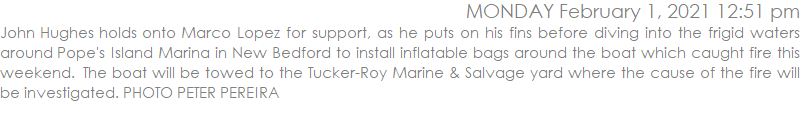 John Hughes holds onto Marco Lopez for support, as he puts on his fins before diving into the frigid waters around Pope's Island Marina in New Bedford to install inflatable bags around the boat which caught fire this weekend.  The boat will be towed to the Tucker-Roy Marine & Salvage yard where the cause of the fire will be investigated. PHOTO PETER PEREIRA