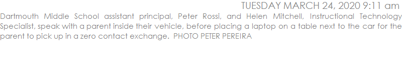 Dartmouth Middle School assistant principal, Peter Rossi, and Helen Mitchell, Instructional Technology Specialist, speak with a parent inside their vehicle, before placing a laptop on a table next to the car for the parent to pick up in a zero contact exchange.  PHOTO PETER PEREIRA