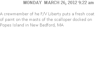 A crewmember of he F/V Liberty puts a fresh coat of paint on the masts of the scalloper docked on Popes Island in New Bedford, MA