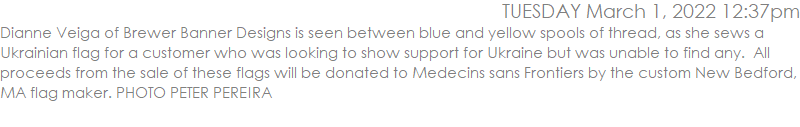 Dianne Veiga of Brewer Banner Designs is seen between blue and yellow spools of thread, as she sews a Ukrainian flag for a customer who was looking to show support for Ukraine but was unable to find any.  All proceeds from the sale of these flags will be donated to Medecins sans Frontiers by the custom New Bedford, MA flag maker. PHOTO PETER PEREIRA