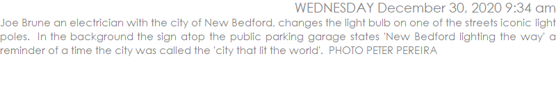 Joe Brune an electrician with the city of New Bedford, changes the light bulb on one of the streets iconic light poles.  In the background the sign atop the public parking garage states 'New Bedford lighting the way' a reminder of a time the city was called the 'city that lit the world'.  PHOTO PETER PEREIRA 