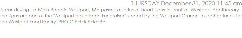 A car driving up Main Road in Westport, MA passes a series of heart signs in front of Westport Apothecary.  The signs are part of the 'Westport Has a Heart Fundraiser