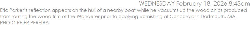 Eric Parker�s reflection appears on the hull of a nearby boat while he vacuums up the wood chips produced from routing the wood trim of the Wanderer prior to applying varnishing at Concordia in Dartmouth, MA. PHOTO PETER PEREIRA