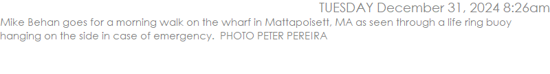 Mike Behan goes for a morning walk on the wharf in Mattapoisett, MA as seen through a life ring buoy hanging on the side in case of emergency.  PHOTO PETER PEREIRA