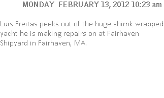 Luis Freitas peeks out of the huge shirnk wrapped yacht he is making repairs on at Fairhaven Shipyard in Fairhaven, MA.