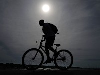 The sun rises on a hazy morning in Mattapoisett as a man rides his bicycle across the wharf.