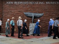 A group of Omish vistors to the city make their way past the whale tail outside of the New Bedford Whaling Museum