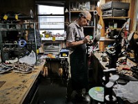 Scott Amorin glues the sole of a shoe he is fixing at the New York Shoe Repair on Dartmouth street in New Bedford.