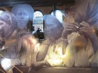 A transparency photo of Cape Verdean immigrants arriving in the United States in 1920 seen behind the model of the Ernestina-Morrissey schooner keep their eyes on a couple making their way across the upper level of the New Bedford Whaling Museum.