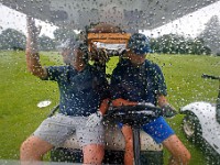 Teammates Eric Bonneau and Adam Mathes take shelter from the driving rain in their golf cart at the 94th Annual Four-Ball Tournament at The Country Club of New Bedford.