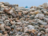 A lobster boat is seen between a trough in the stones piled up on the edge of East Beach Road in Westport.