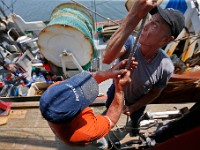 Steve Lacombe and Ken Shneider hoist the mast of the Kyler C fishing boat as they prepare to unload it at the Whaling City Seafood Display Auction building on Hassey Street in New Bedford.