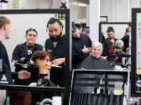 Rob Roy Academy instructor Lucas Hernandez is reflected in the mirror on the left as he inspects a preparation test being performed by a student, in the background Nathan Dorego gives Joe Correia a haircut at the Rob Roy Academy barber school in Fall River.