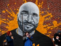 People waiting for the bus have big company in the mural of a man painting on a building on Pleasant Street in New Bedford.