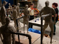 Clay on wire figures from body as concept class look on as Katie Erwin and Maddie Gonzalez work on the head of the nips bottles monster.  The 'Monster Creature from the Plasticine Era' made with over thirty two thousand discarded nips bottles around a metal framework, will be marched by students in the upcoming A-Ha Earth Eve Procession in downtown New Bedford.