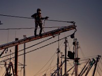 A painter looks ready for outer space exploration as he uses a pneumatic needle scaler to remove the rust from the outrigger of a fishing boat he is painting in New Bedford.