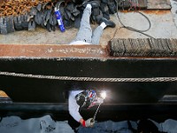 Kevin Raposo, deckhand aboard the fishing boat Chandler Rae, finds himself half in and out, as he makes repairs to the scupper of the New Bedford scalloper docked at State Pier before heading out to sea.