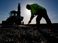 Fernando Conde of New Bedford DPI shovels gravel into a sink hole which was created after waves crashed into the side of a pier on East Beach due to a storm last week.