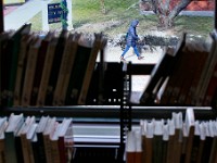 A woman makes her way to New Bedford City Hall as seen through a gap in the books at the New Bedford Public Library.