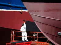 A painter puts a fresh coat of paint on the hull of a fishing boat undergoing repairs at Fairhaven Shipyard.