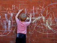 A young boy in the YMCA Preschool program in downtown New Bedford, lets his creativity flow with caulk on the building's red brick wall.