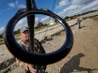 With finger on the line, Arlindo Vitorino is seen through one of the guides on his fishing rod as he and Herve Fernandes are seen fishing at Fort Taber Park in New Bedford. PHOTO PETER PEREIRA