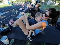 Sarah Freshman tries to work with weights as her son Wesley Freshman, 1, rests on her chest during the I Stroll Southcoast weekly workout session at Cushman Park in Fairhaven for mom with young children who want to work out.