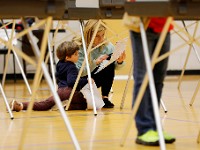 Maggie Toland kneels down so her son Cameron Kennedy, 4, can be part of her voting process at the Fairhaven Recreation Center polling staion on Election Day, Nov. 5, 2024.