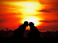 A couple kiss while sitting atop on outcrop at Fort Phoenix in Fairhaven as the sun sets in the distance.