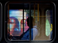 A man rides the bus as it makes its way past the mural of a Buddah painted on the side of the Spicy Lime building in downtown New Bedford.