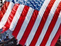 A fisherman on a scalloper tied in New Bedord harbor is seen behind the American flag hanging from the stern of the schooner Ernestina-Morrissey at State Pier.