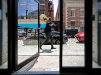 Hugo Amarante walks up William Street with a guitar on his shoulder past the open door of an apartment complex.  When asked where he played his guitar, he responded "If someone needs to feel better, I will play the guitar for them"